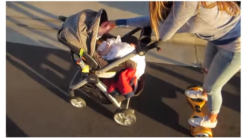 mom on hoverboard feeding baby in stroller